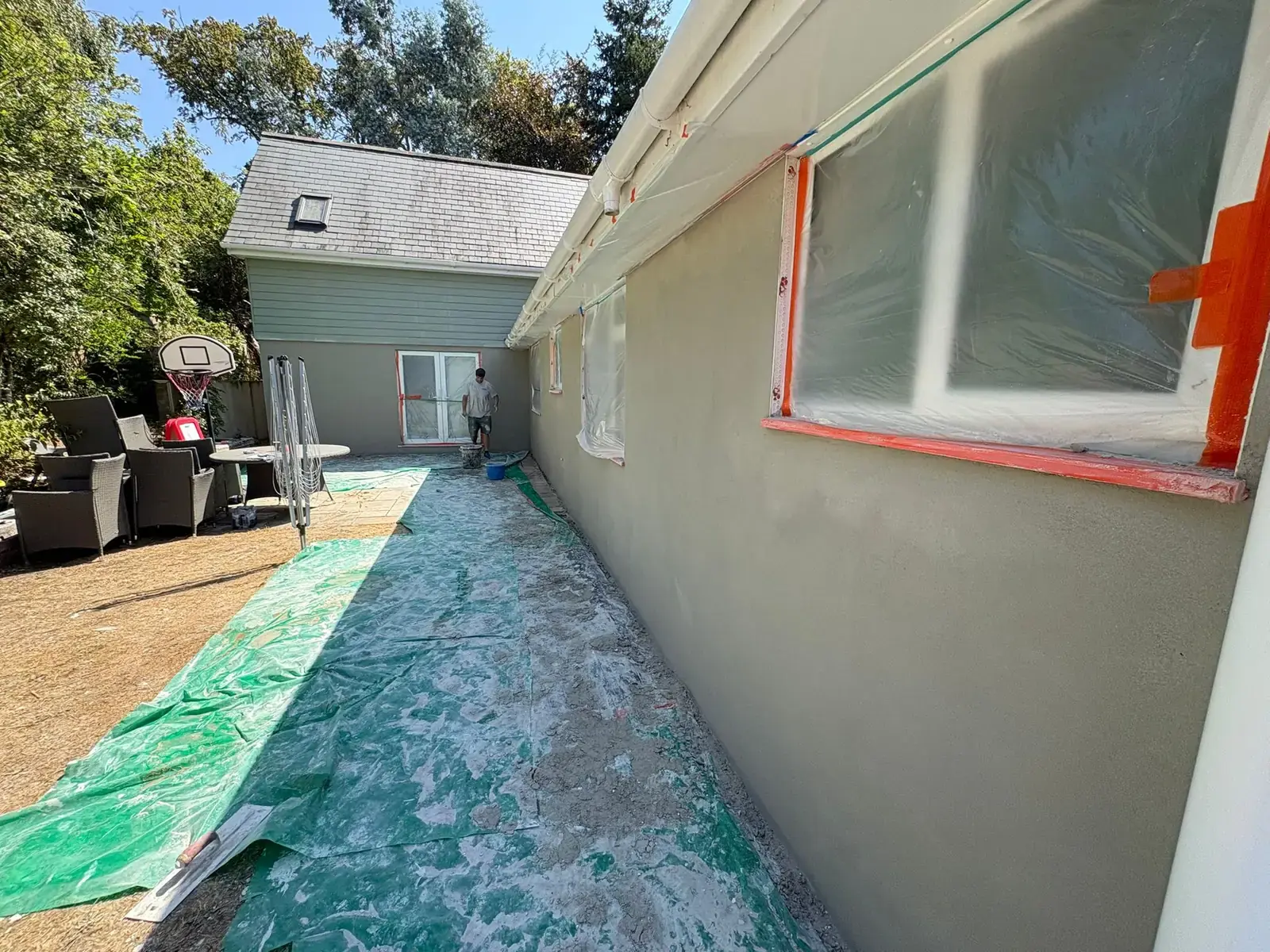 Long side elevation of an annexe with fresh grey base coat, windows masked with plastic and orange tape