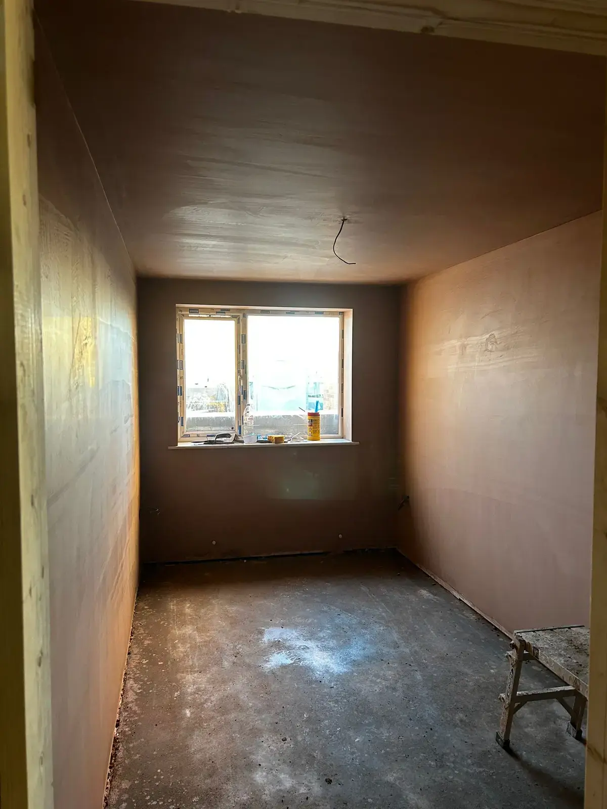 Empty bedroom freshly plastered, window letting in light