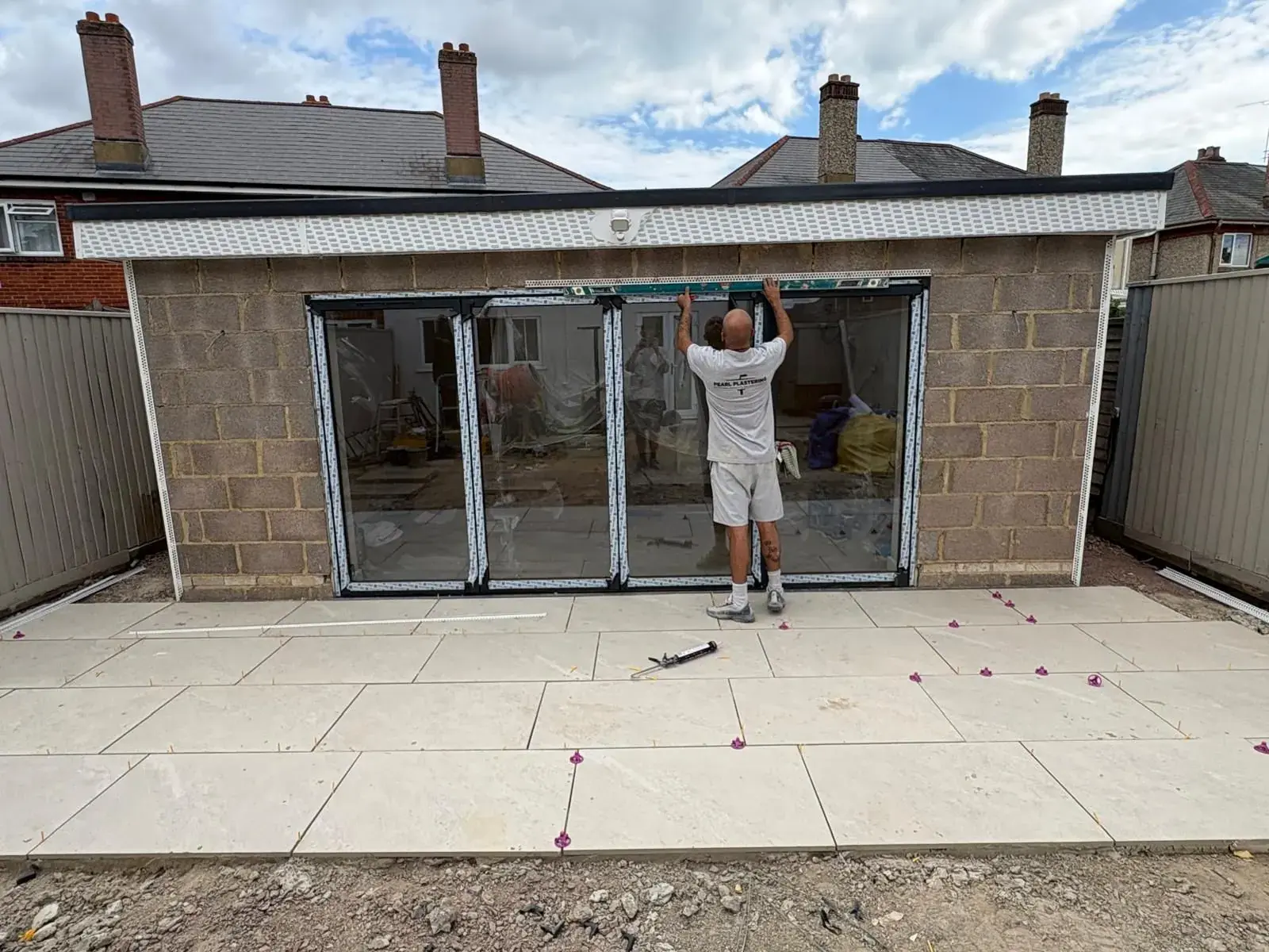 Blockwork rear extension with bifold doors being fitted, new patio slabs laid in front, walls waiting for render