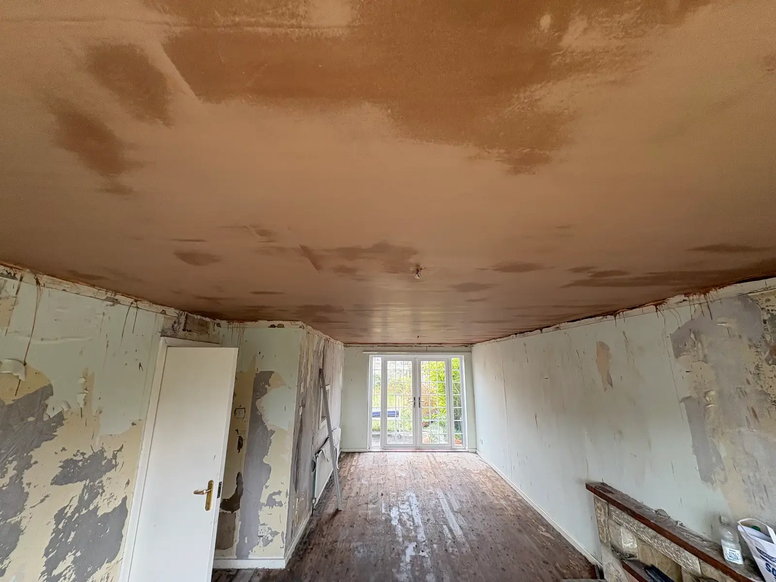 Pre-renovation room with French doors and a freshly plastered ceiling