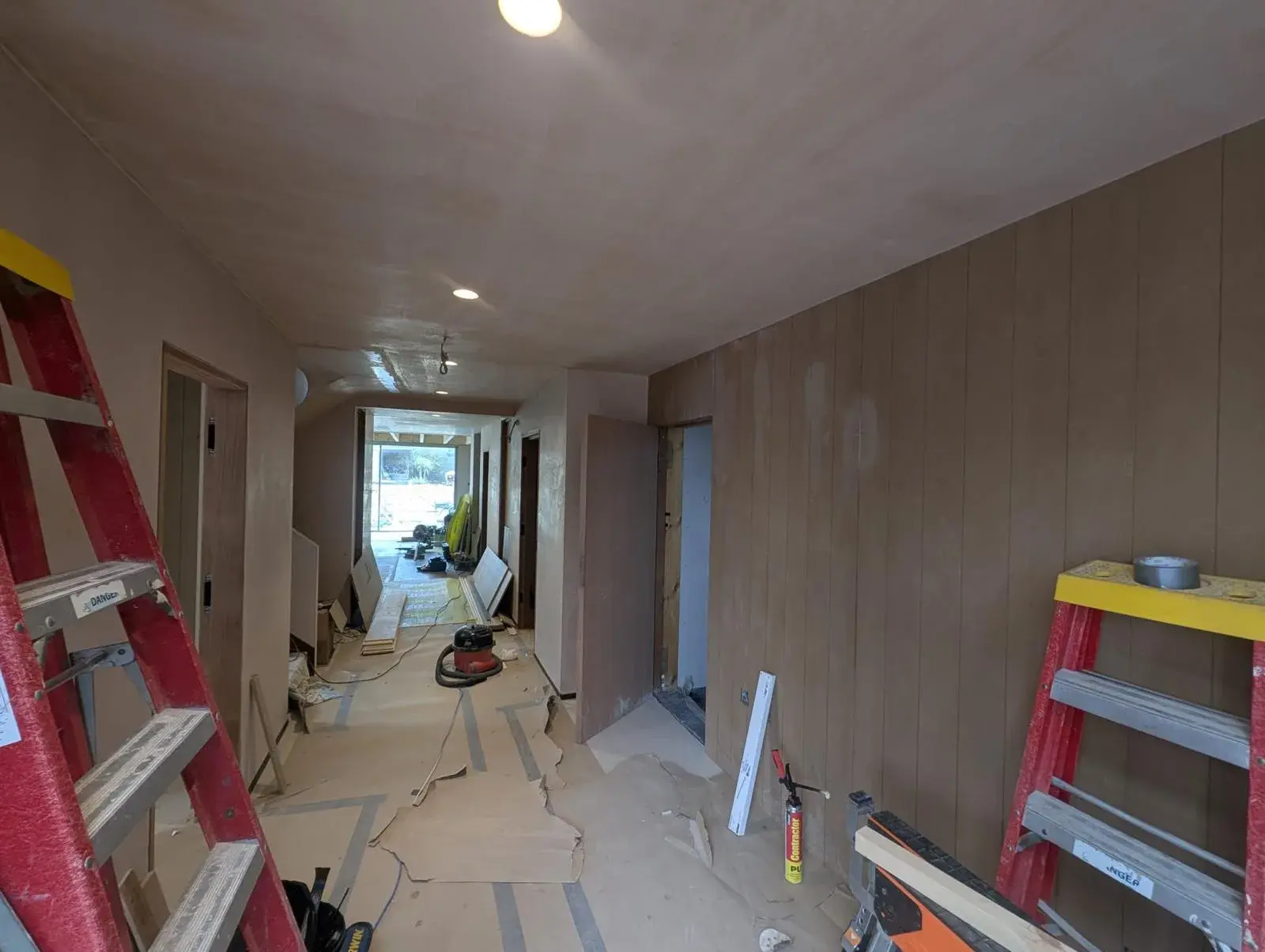 The Pearl Plastering team mid-skim on a Dorset hallway, dust sheets down, ladders set