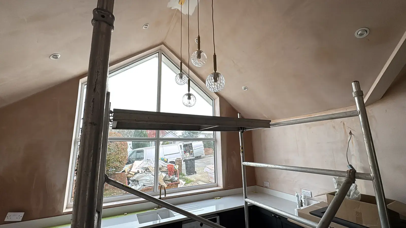 Plastered vaulted interior with scaffold tower and large triangular window